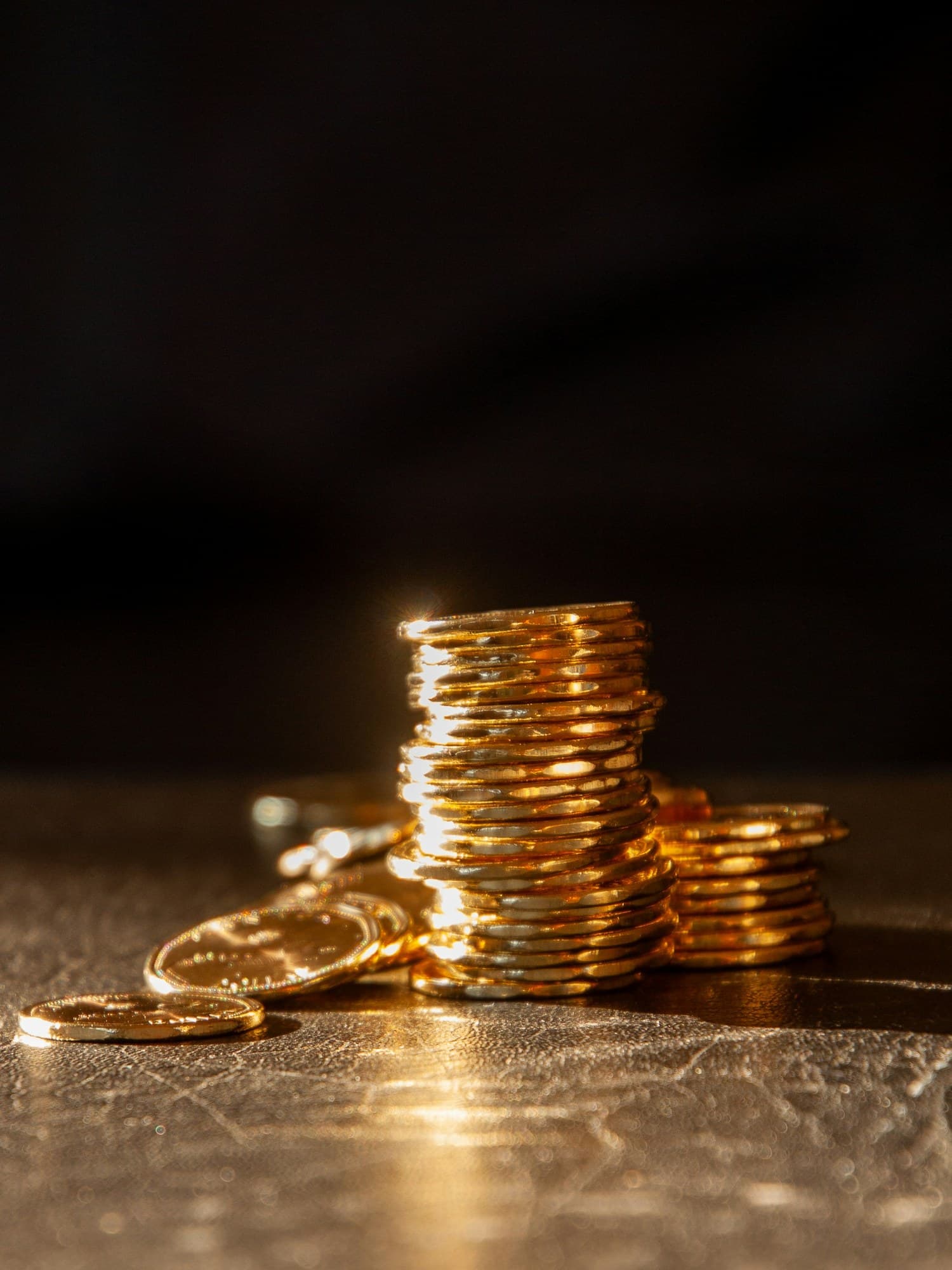Stacks of gold coins on a dark surface, representing the kind of bullion and rare-coin holdings Park Avenue Numismatics appraises every day